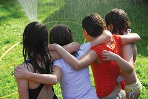 girls arm in arm around a sprinkler