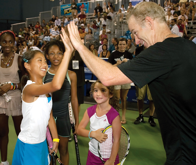 Photo courtesy Sportime John McEnroe high-fives student at his tennis academy try outs.