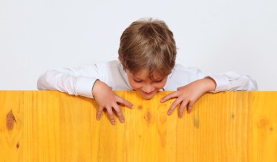 Curious boy peers over fence